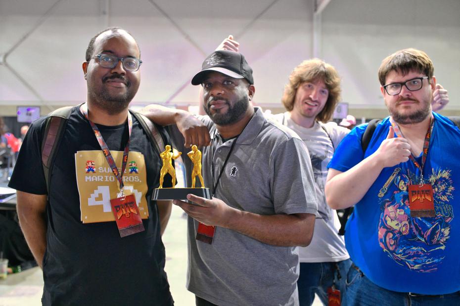 WhoDat poses with his mystery tournament trophy. Left: DragonCharlz. Right: coderius, senkou0.