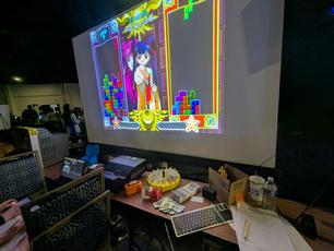 Tetris with Cardcaptor Sakura for the PlayStation. The game cards and roulette wheel can be seen on the table below. A small monitor with game instructions is placed near the players.